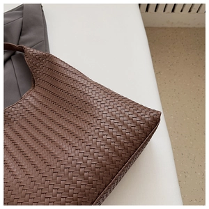 Detailed macro shot of vintage brown woven leather tote bag with intricate texture