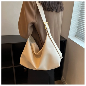 Detail of creamy white large shoulder bag featuring wide strap and golden metal buckle