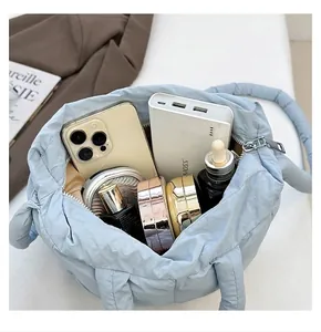Dettaglio dell'interno capiente della borsa trapuntata azzurra con oggetti quotidiani