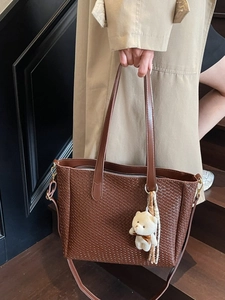 Deep brown woven tote bag with adjustable strap and plush bear charm for daily commute