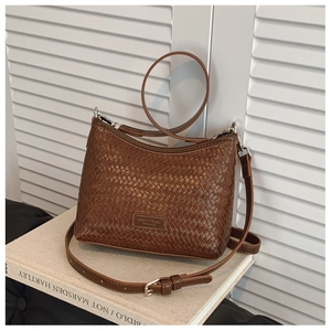 Detail of a dark brown bucket bag with woven texture and adjustable silver metal buckle