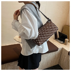 Polka dot pillow bag in dark brown with leather strap worn over shoulder in lifestyle setting
