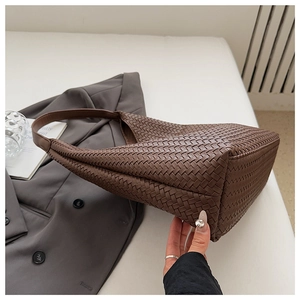 Detailed close-up of coffee brown woven leather tote bag with classic hobo structure