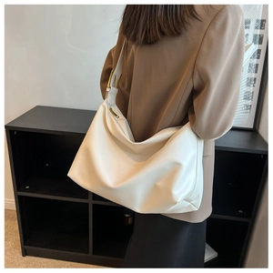 Model view showing the back side of a white minimalist hobo shoulder bag with gold hardware