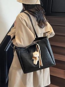 Retro black woven leather tote bag with plush bear charm worn by model on stairs