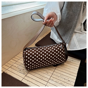 Close-up of brown polka dot barrel bag with synthetic leather strap in indoor setting