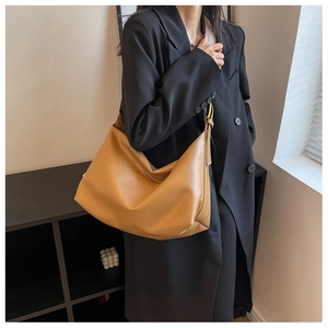 Detailed view of camel faux leather tote bag styled with a professional black blazer