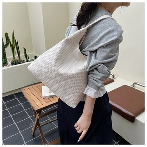 Detail of a beige woven leather hobo bag showing texture in a casual outdoor setting