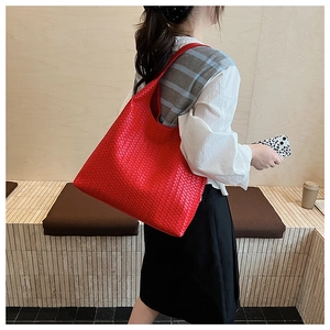 Detail of red woven tote bag showing large capacity and soft leather texture on shoulder