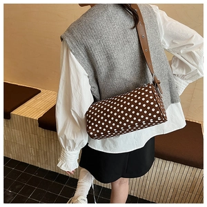 Detail of adjustable brown leather strap and silver metal buckle on polka dot pillow bag