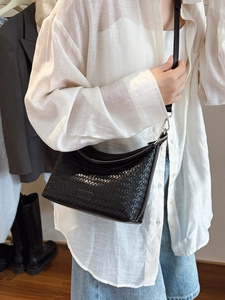 Classic black woven bucket bag with elegant shoulder strap shown on a model