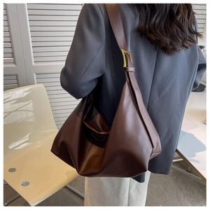 Detail view of large brown faux leather tote with adjustable strap and gold metal buckle