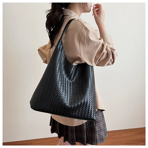 Detailed view of the black leather woven texture on a large capacity tote shoulder bag