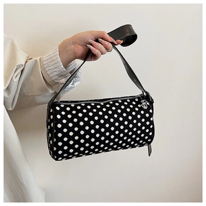 Close-up of a black and white polka dot cylindrical shoulder bag with silver zipper