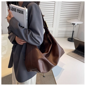 Detail of a large brown hobo shoulder bag with matte finish and gold metallic buckle