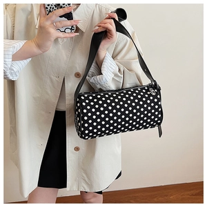 Close-up of stylish black and white polka dot cylinder bag with wide leather strap