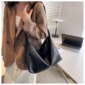 Matte black oversized tote bag shown on shoulder with minimalist business casual outfit