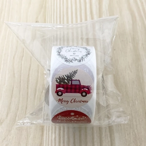 Close-up of Christmas roll stickers with Merry Christmas text on light wood background
