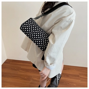 Detail of trendy polka dot pillow bag with wide leather shoulder strap on model