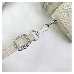 Close-up of white lace texture and adjustable silver metal buckle on elegant box bag