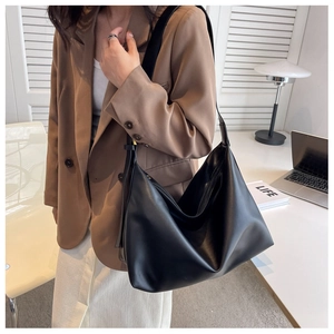 Detailed view of black PU leather hobo bag worn by model in a minimalist office setting
