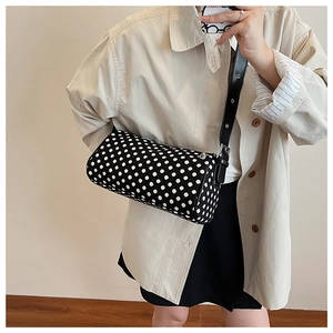 Close-up of black and white polka dot cylinder bag with adjustable leather shoulder strap