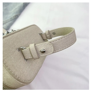 Close-up of Saffiano leather texture and silver metal rings on a beige crossbody bag