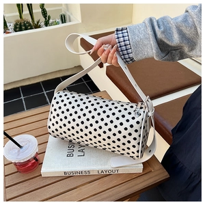 Detail of polka dot boston bag with silver zipper and white leather strap in cafe setting