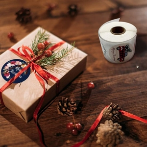 Close-up of Merry Christmas stickers on a gift box with a wood and pinecone background