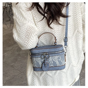 Detail of blue denim and white lace box bag with adjustable strap and leather trim