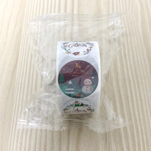 Detail of Christmas round sticker roll with snowman and reindeer patterns on wood background
