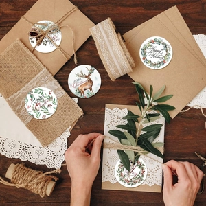 Gros plan d'autocollants ronds de Noël avec motifs de rennes et fleurs sur enveloppes