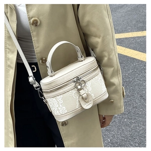 Detailed view of women's white lace cylinder bag with adjustable strap and top handle