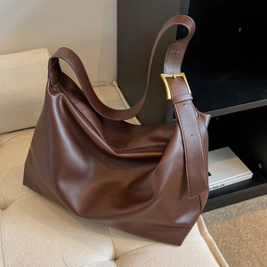 Minimalist deep brown large hobo shoulder bag with golden buckle on off-white sofa