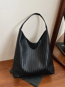Large black woven leather hobo bag with V-shaped texture on vintage green books