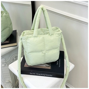 Detail of light green quilted down bag texture with soft top handle and shoulder strap