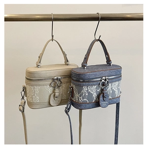 Detail of elegant lace-covered box bags in beige and blue denim with top handles