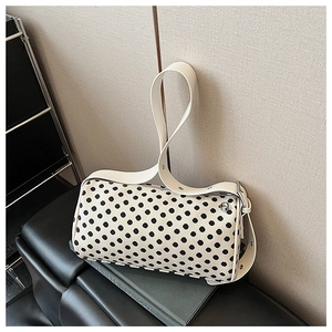 Detailed view of polka dot cylinder bag with zipper closure and white wide shoulder strap