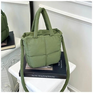 Detailed view of green quilted puffer bag with soft padding and wide shoulder strap