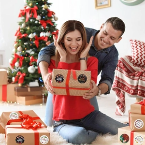 Couple exchanging gifts with Merry Christmas stickers on kraft paper boxes