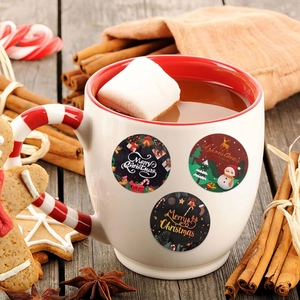 Close-up of circular Merry Christmas stickers on a mug in a cozy holiday setting