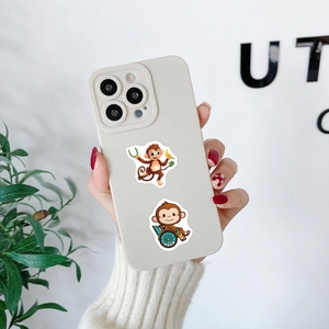 Handheld view of cream silicone iPhone case featuring cute cartoon monkey patterns