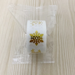 Macro shot of gold foil Christmas stickers featuring Merry and JOY text on rolls