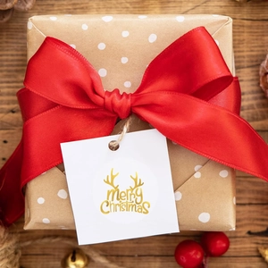 Close-up of brown polka dot gift wrap with a red satin bow and Merry Christmas tag