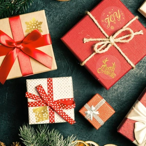 Flat lay of Christmas gift boxes with gold foil JOY lettering and holiday decorations