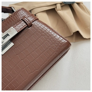 Detailed close-up of dark brown crocodile embossed leather and silver metallic twist lock