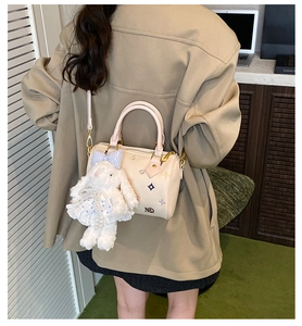 Detail of beige Boston bag with star embroidery and cute plush rabbit charm