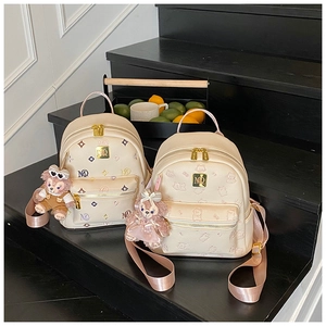 Detail of cream leather mini backpacks with MQ logo, embossed bears, and plush charms