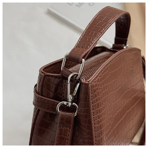 Close-up of brown crocodile pattern handbag with silver hardware and sturdy top handle
