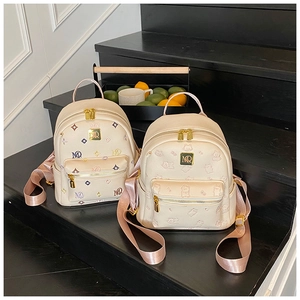 Close-up of beige mini backpacks with gold hardware and pink silk-textured straps